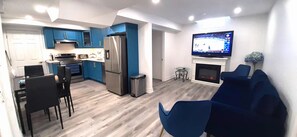Eine moderne Küche mit blauen Schränken, einem Edelstahlkühlschrank und einem Essbereich mit schwarzen Stühlen.