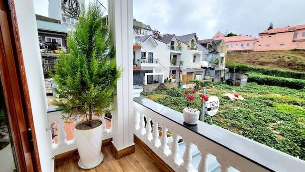 A balcony with a potted tree, a sign indicating a garden area, and a view of neighboring houses. - Entire Home: Beautiful, Brand-new built in 2022 (Phuong 6, Da Lat city)