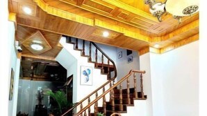 A wooden staircase with a wooden desk and plants, leading to a living area with a sofa and ottomans. - Entire Home: Beautiful, Brand-new built in 2022 (Phuong 6, Da Lat city)