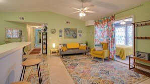 A living room with a sofa, yellow armchair, and a coffee table. There is a kitchen area with a counter and stools. - 2 Mi to Surfside Beach! Condo w/ Community Pool (Myrtle Beach)