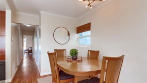 A dining area with a round wooden table, six chairs, a potted plant, and a wall-mounted mirror. - Ocean view! Walk to Sunset Cliffs - Surf - Beach! (San Diego)