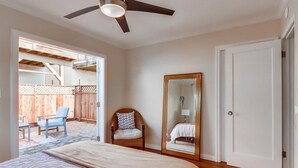 A bedroom with a bed, a ceiling fan, a large mirror, and a view of an outdoor patio with a chair and a table. - Ocean view! Walk to Sunset Cliffs - Surf - Beach! (San Diego)