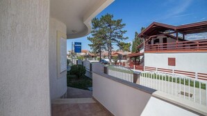 A balcony with a view of a residential area, a clear sky, and a building with a red roof. - Apartments Anamarija - One Bedroom Apartment with Balcony (Privlaka)