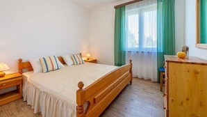Una camera da letto con un letto di legno, un comodino, una cassettiera e una finestra con tende verdi.