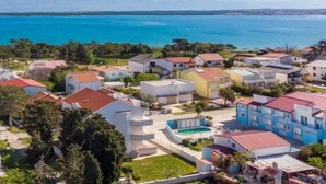 Ett bostadsområde vid kusten med hus, en swimmingpool och utsikt över havet.