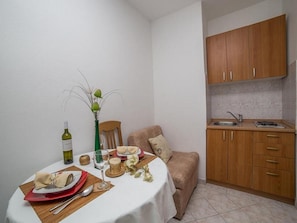 Un espacio habitable compacto con zona de comedor, kitchenette y sofá.