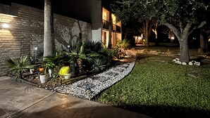 A modern house with a stone facade, a well-maintained lawn, and a pathway leading to the entrance. - Tropical Garden Oasis  • Birdwatcher's Paradise • Spacious Harlingen Retreat (Harlingen)