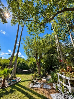 A garden with a hammock, potted plants, and a wooden fence.