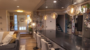 A modern kitchen with a central island, bar stools, and pendant lighting. - Tropical Garden Oasis  • Birdwatcher's Paradise • Spacious Harlingen Retreat (Harlingen)