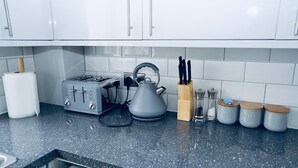 Eine Küche mit weißen Schränken, einem Toaster, einem Wasserkocher, einem Messerblock und Gewürzgläsern.