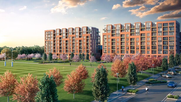 Ein moderner Apartmentkomplex mit mehreren Stockwerken, großen Fenstern und einer gepflegten Umgebung mit Bäumen und einem Parkplatz.