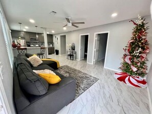 Relax in this stylish living room with a sofa, ceiling fan, and kitchen area.