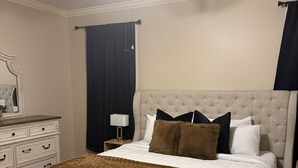 Ein Schlafzimmer mit einem Bett, einer Bank, einem Deckenventilator, einem Schminktisch und einem Nachttisch.