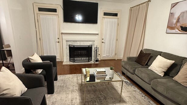 Ein Wohnzimmer mit Kamin, Deckenventilator, Flachbildfernseher und einem grauen Sofa.