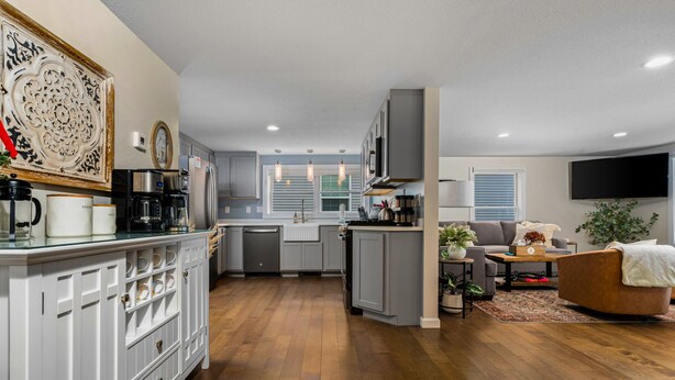 Una cocina moderna con armarios blancos, una isla central y una zona de comedor con sofá y mesa de centro.
