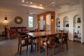 A dining area with a wooden table and chairs, a sofa, and a decorative wall shelf.