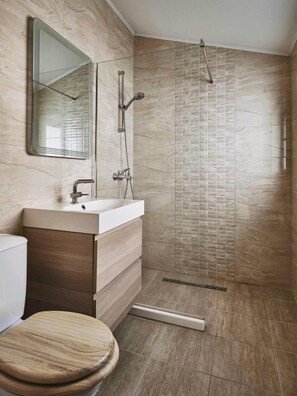 A modern bathroom with a wooden vanity, a large mirror, a shower with a glass door, and a tiled floor. - Magnificent Sea View Penthouse Sozopol (Sozopol)