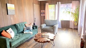 A cozy living room with a green sofa, a grey armchair, and a wooden coffee table.