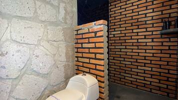 Un baño con inodoro, ventana y pared de ladrillo.