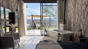 Un dormitorio moderno con una cama grande, una zona de estar y vistas a un lago.