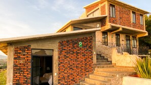 Un edificio de dos pisos con fachada de ladrillo, un balcón y una escalera que conduce al nivel superior.