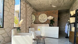 Zona de recepción de un spa con paredes de piedra, un mostrador y áreas de estar.
