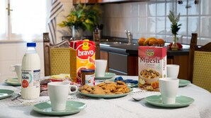 Una mesa de desayuno con platos de galletas, una botella de leche, un cartón de jugo de naranja y una caja de cereales.