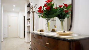 Un baño con tocador de madera, un espejo y un florero con flores rojas.