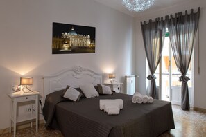 A neatly arranged bedroom with a large bed, two bedside tables with lamps, a framed picture on the wall, and a view through the window. - Bonifacio VIII (Rome)
