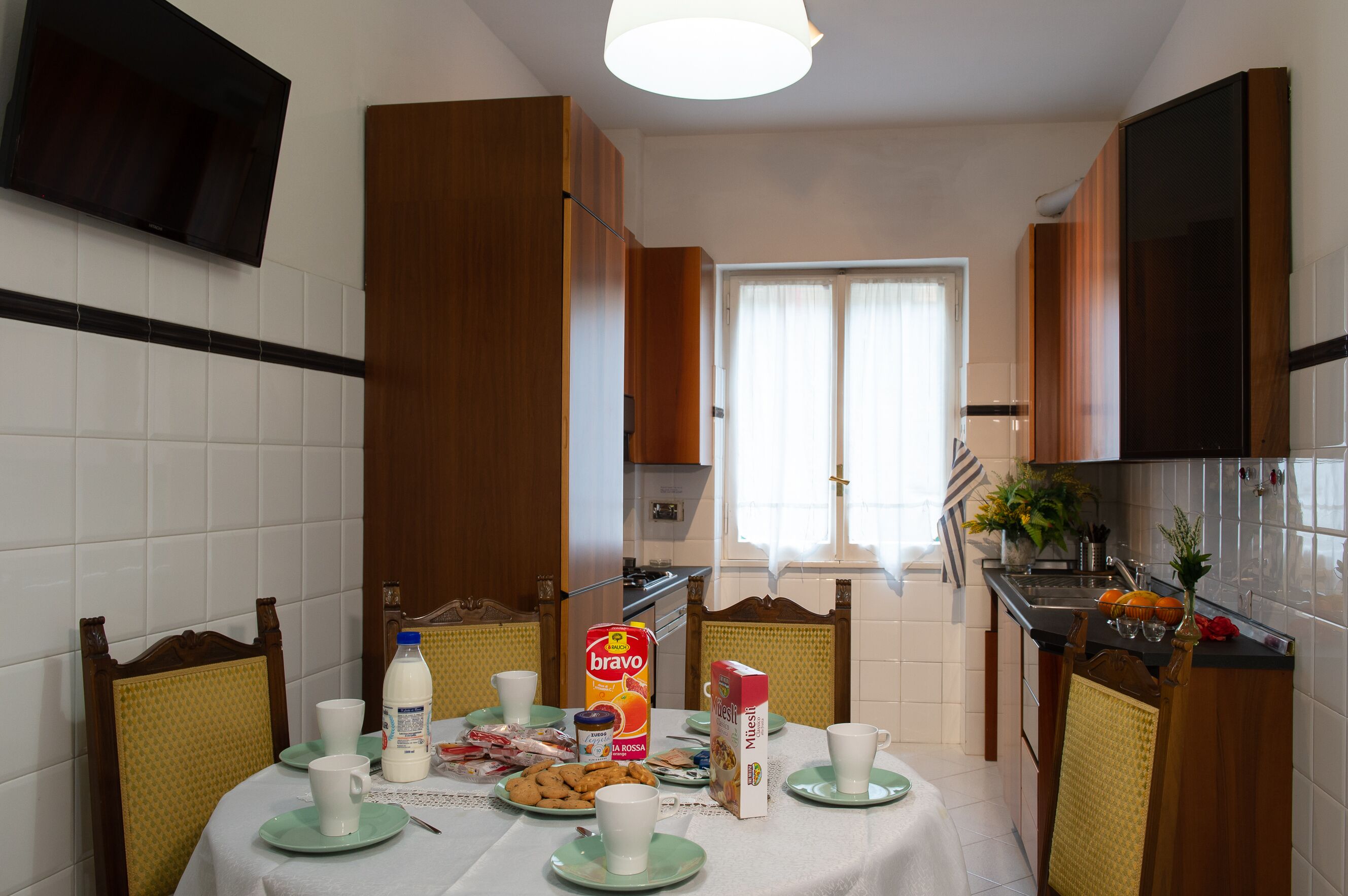 A kitchen with a dining table set for breakfast, including plates, cups, and a carton of milk.