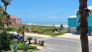 A residential street with a view of the ocean, palm trees, and houses.