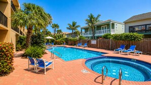 Ein Swimmingpool mit Liegestühlen, Palmen und einer Pflasterterrasse.