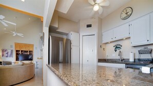 A modern kitchen with granite countertops, stainless steel appliances, and white cabinetry. - La Solana 118 A Bayview paradise - approved pets only (South Padre Island)