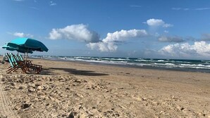A beach with a clear sky, waves, and a blue umbrella. - La Solana 118 A Bayview paradise - approved pets only (South Padre Island)