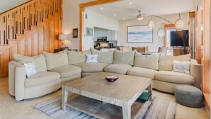 A spacious living room with a large sectional sofa, a wooden coffee table, and a staircase with wooden railings. - La Solana 118 A Bayview paradise - approved pets only (South Padre Island)