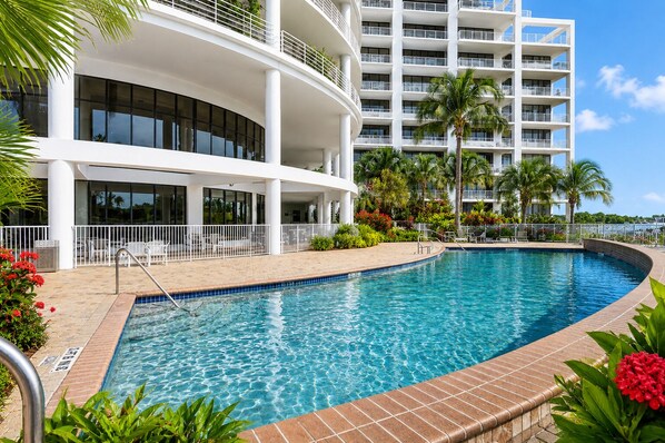 Un hotel moderno con piscina, mobiliario exterior y vista al océano.