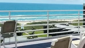 A balcony with white chairs and a view of the ocean. - Sunchase Resort Condo 20 ft glass view 4-min to water (South Padre Island)