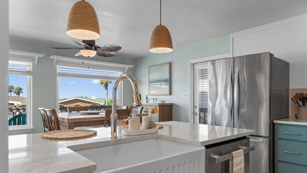 A modern kitchen with a large island, stainless steel appliances, and a view of the outdoors.