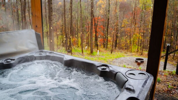 A hot tub with a view of a forest. - Treetop Escape | Hot Tub, Hiking, Movie Theater & 5 Private Acres! (Logan)