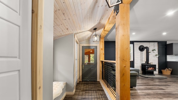 Un corridoio con soffitto in legno, una panca, una porta e un caminetto sullo sfondo.