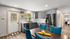 Una cucina moderna con mobili grigi, elettrodomestici in acciaio inossidabile e un'area pranzo con sedie blu.