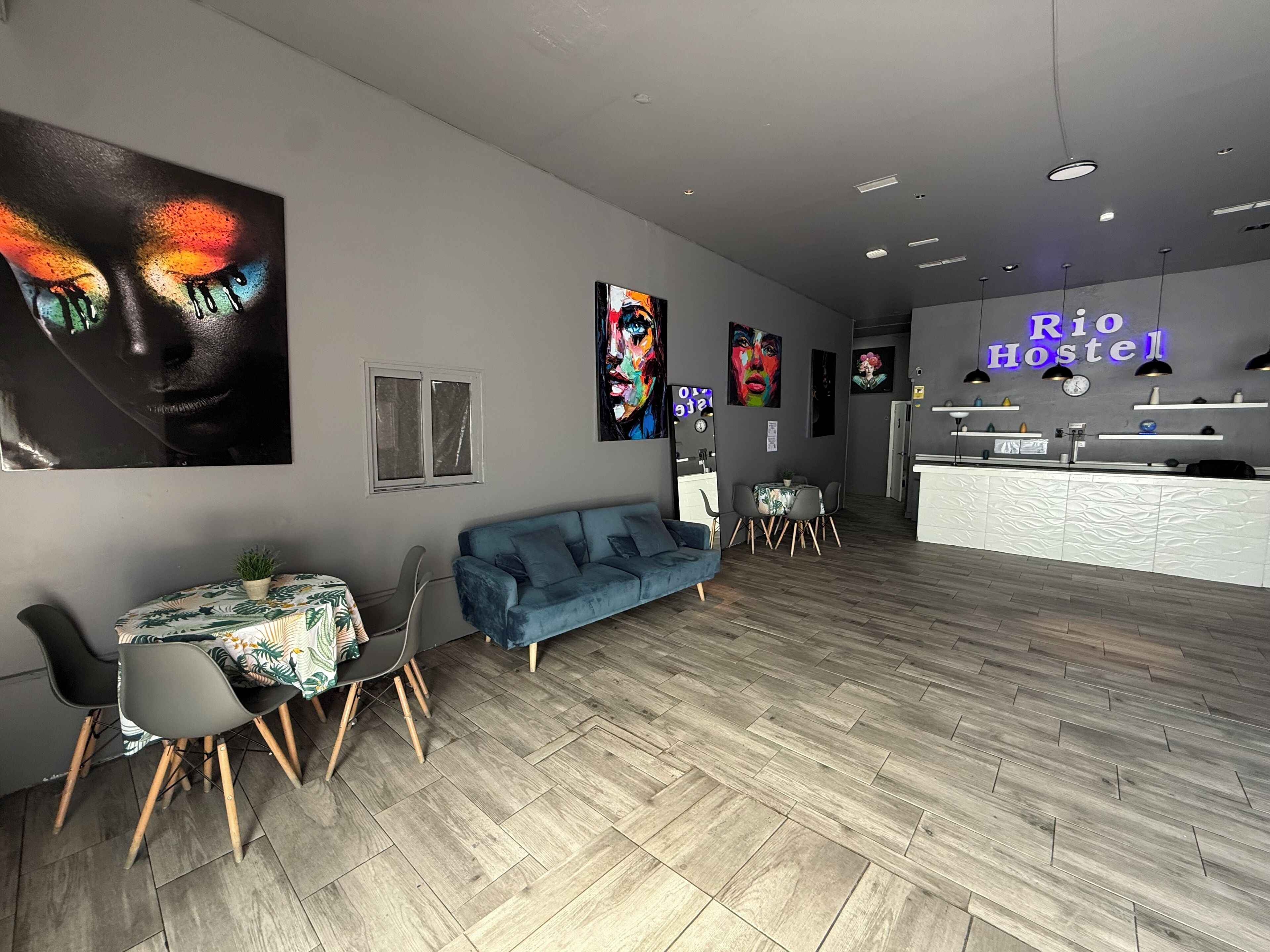 A modern hostel interior with a reception desk, seating area, and artwork on the walls.