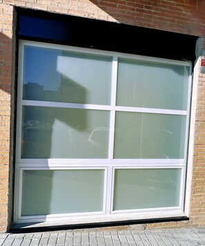 A large window with multiple panes, reflecting a clear sky and some buildings.