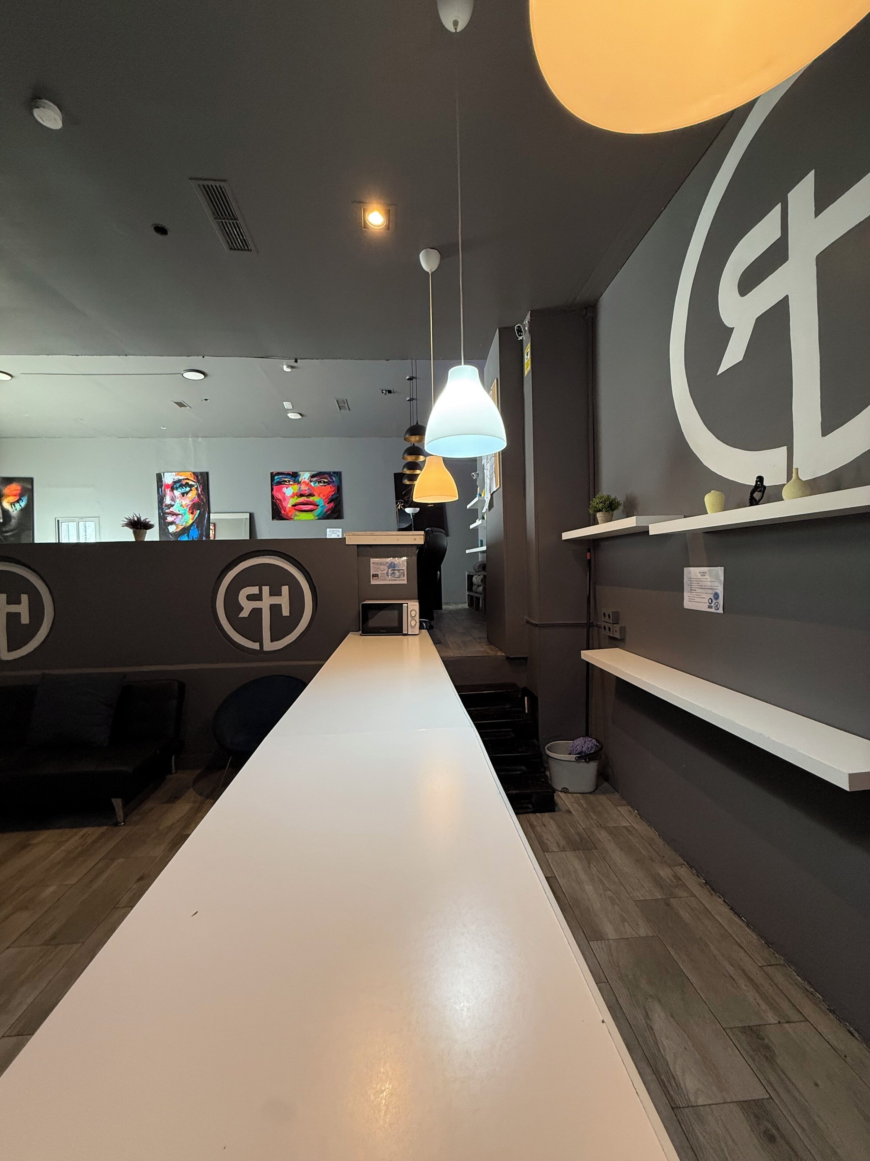 A modern interior with a long white counter, pendant lighting, and artwork on the walls.