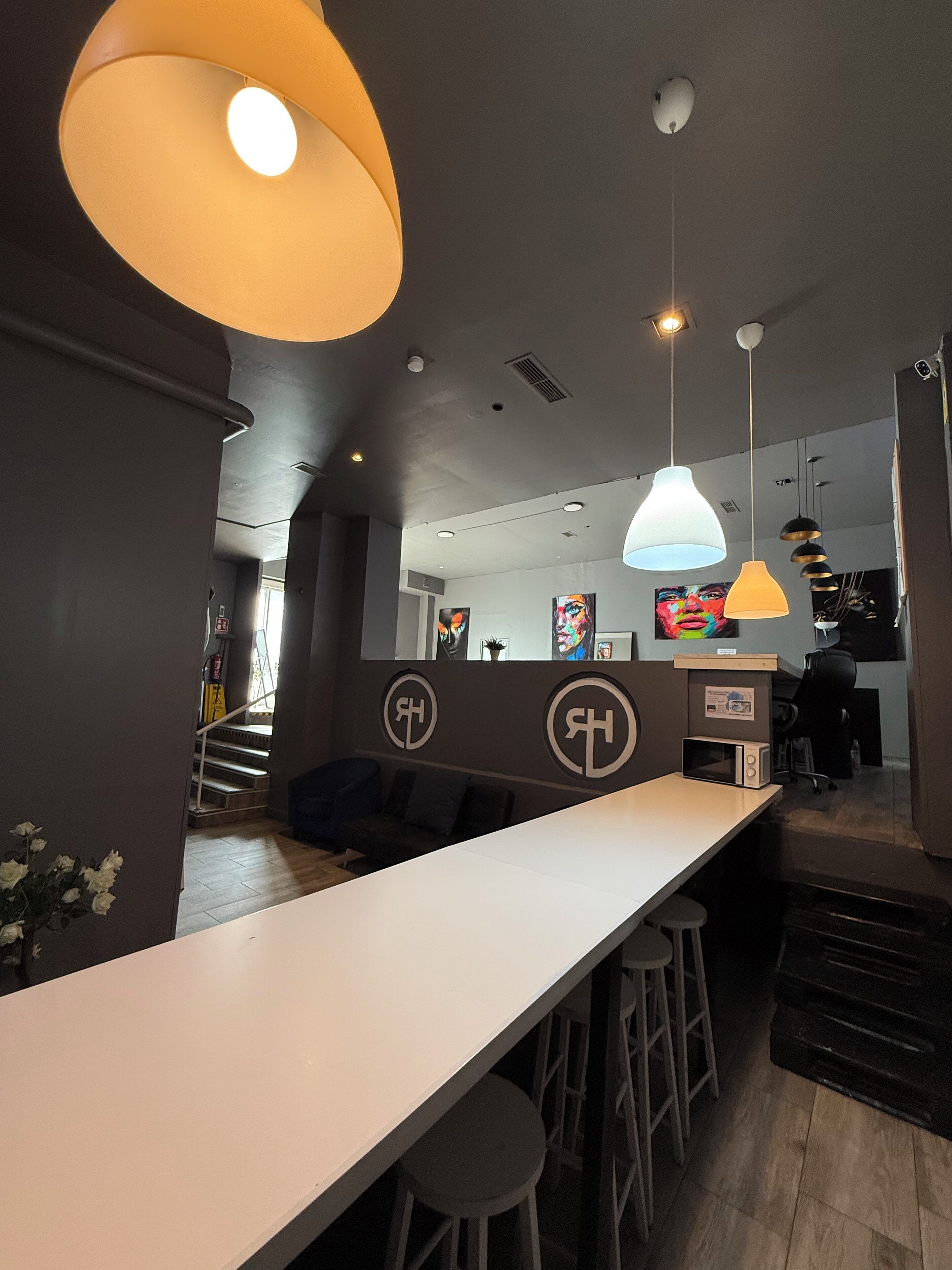 A modern bar area with a long counter, stools, and pendant lighting.
