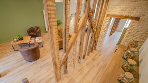 Un interior moderno con piso de madera, una pared de piedra y un área de estar con una mesa y sillas.