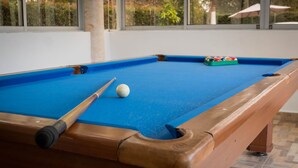 Une table de billard recouverte d’un drap bleu, une queue de billard et une bille blanche.