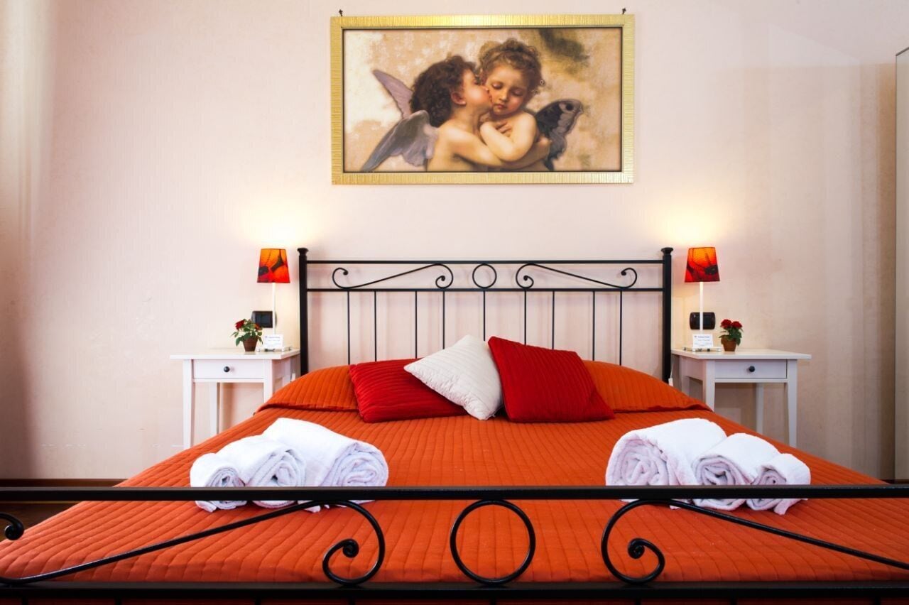 Ein Hotelzimmer mit Bett, zwei Nachttischen mit Lampen, einem Bild an der Wand und Handtüchern auf dem Bett.