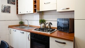 Una cocina con gabinetes blancos, estufa a gas, hervidor y tostadora.