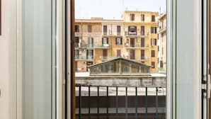 Una habitación con puerta de vidrio corrediza que da a un balcón con barandilla de metal.